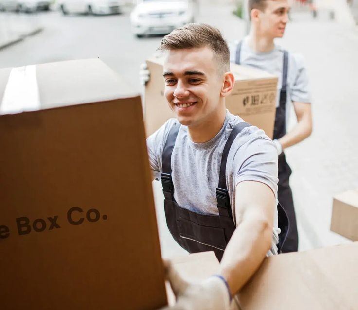 Two smiling small business owners packing products in a shop with clothing racks and a laptop, showcasing the need for secure and flexible business storage solutions.